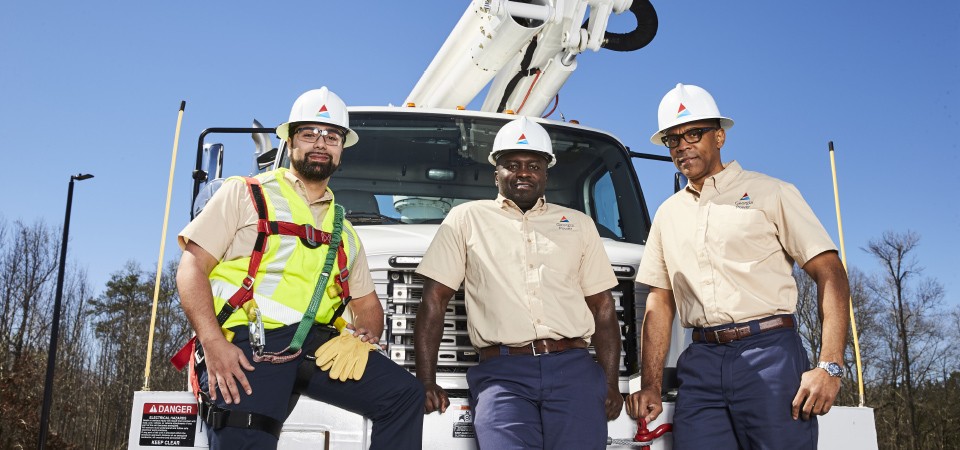 linemen stand in front of truck