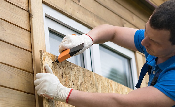 man boarding up windows