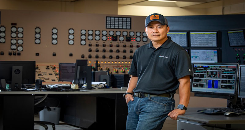 Len monitors plant performance data in a control room at Plant Scherer, surrounded by digital screens and control systems.